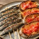 Plato de Pan Tumaca con Espetos de Sardinas Crujientes, deliciosa tapa española.